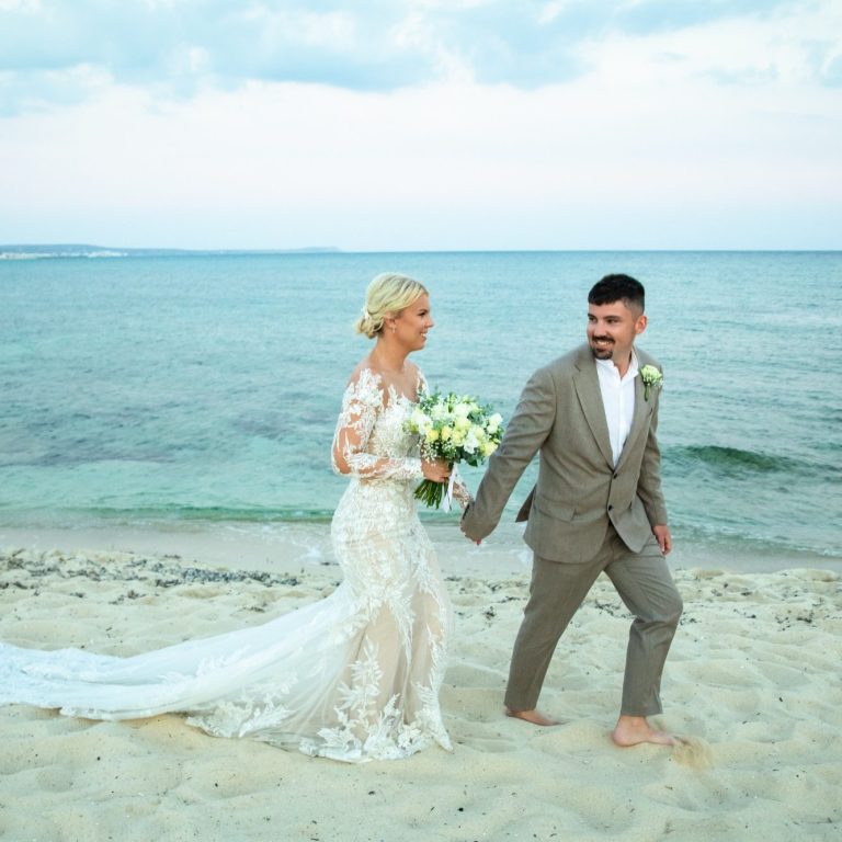 Newlyweds walking hand-in-hand on the beach after their wedding ceremony, officiated by Molly's Ceremonies.