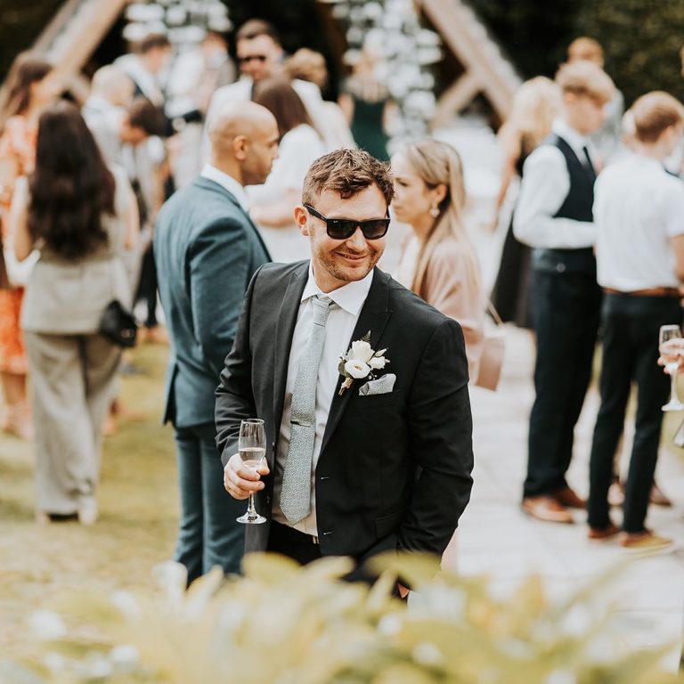 Wedding guest holding a glass of champagne in a garden in Chester during a wedding ceremony officiated by Molly's Ceremonies.