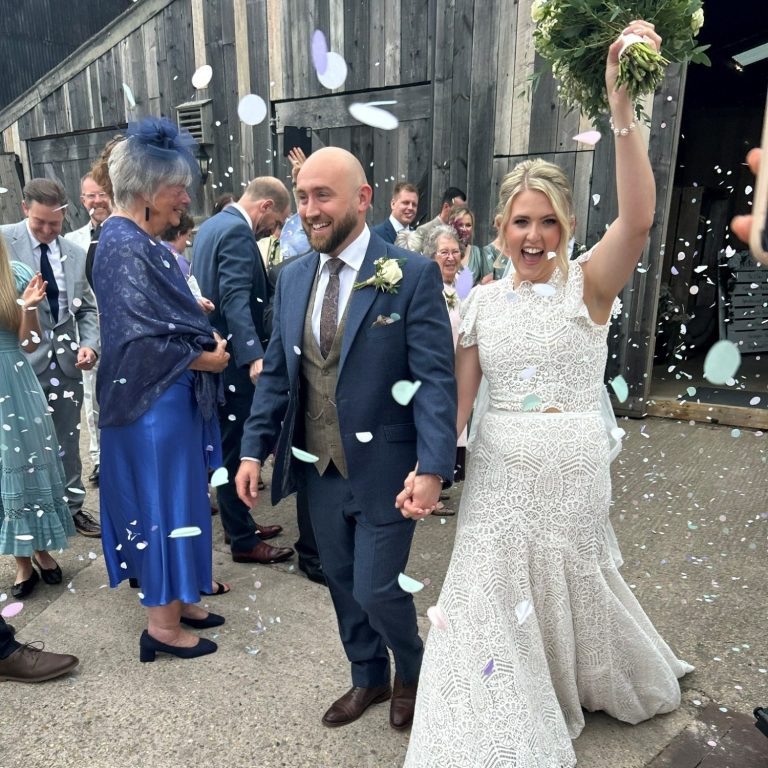 Super happy couple celebrating after tying the knot, with guests in the background throwing confetti in Cheshire.