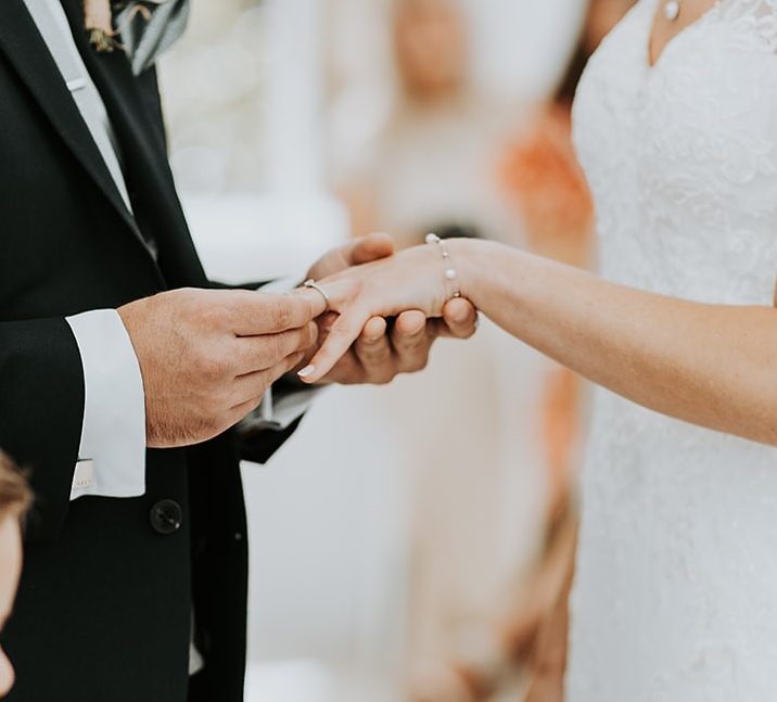 Close-up of a groom placing a wedding ring on the bride's finger during a ceremony, officiated by Molly's Ceremonies in the North West