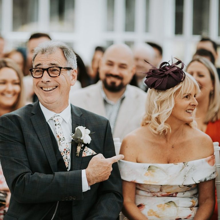 Wedding guests seated during the ceremony, laughing and enjoying the moment.